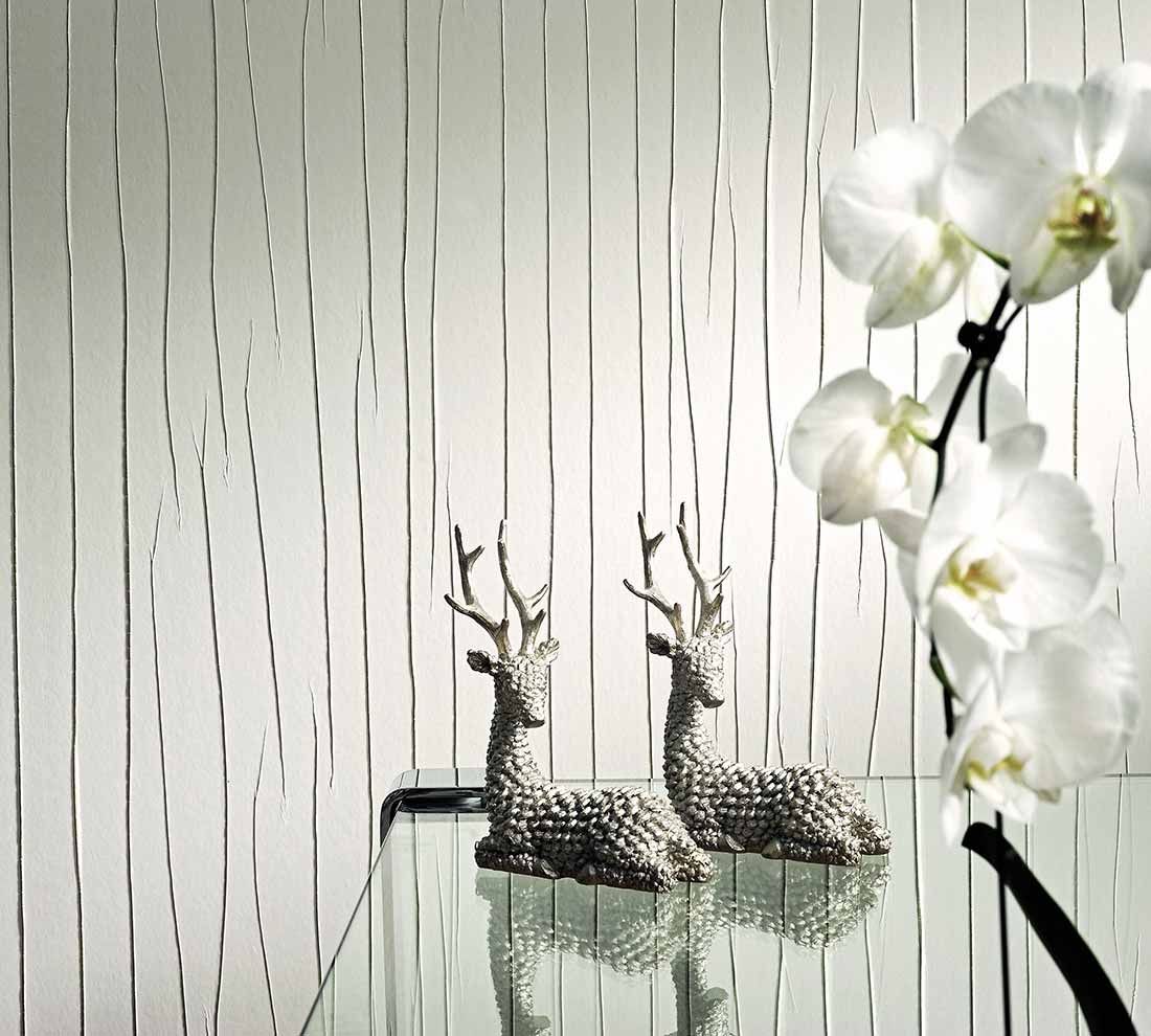 Eine cremefarbene Crush-Tapete in Knitteroptik hinter einem gläsernen Beistelltisch mit Orchidee und zwei Deko-Rehen