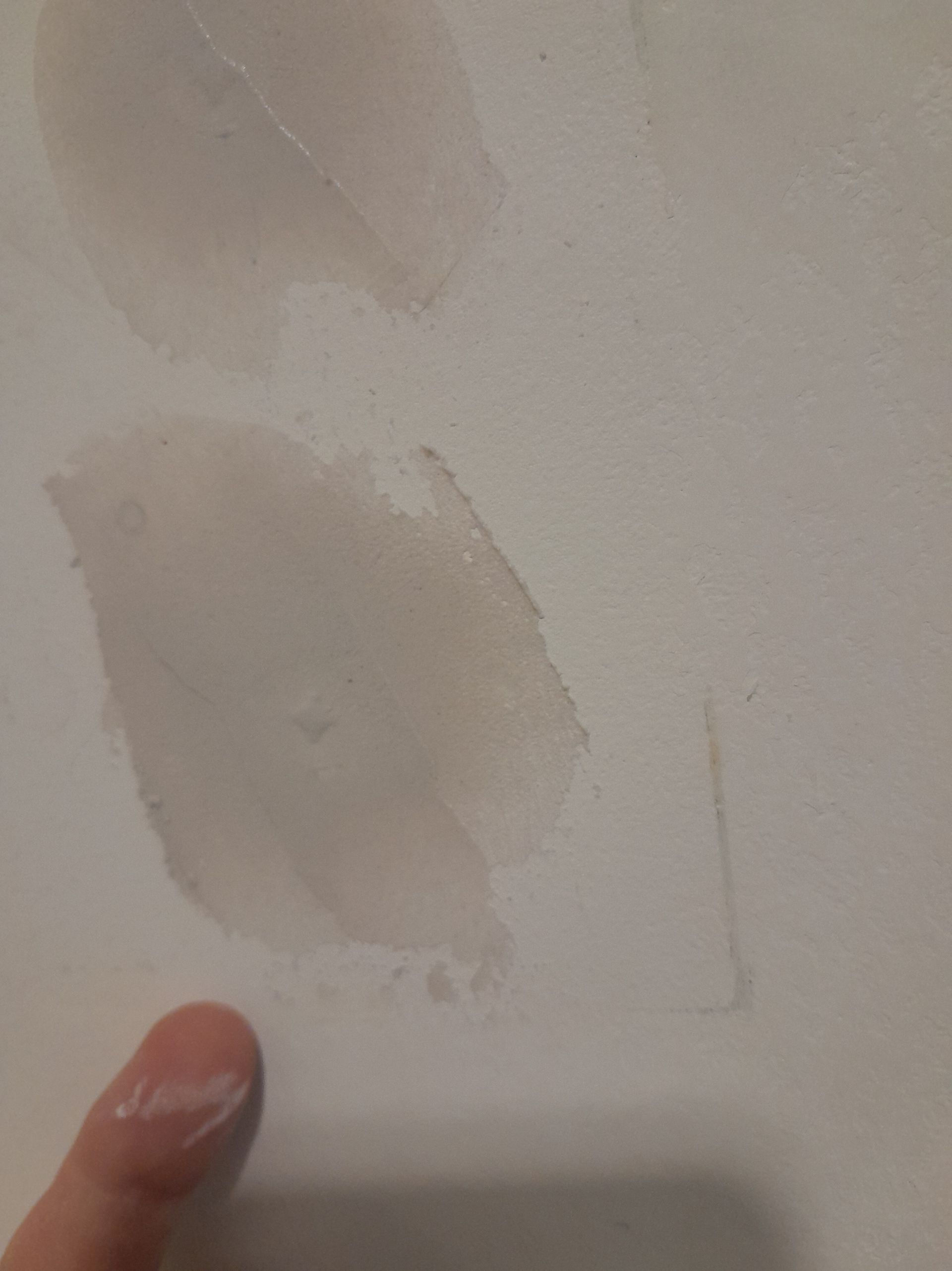 Hand fühlt unebene Stellen auf einer Wand für das Spachteln