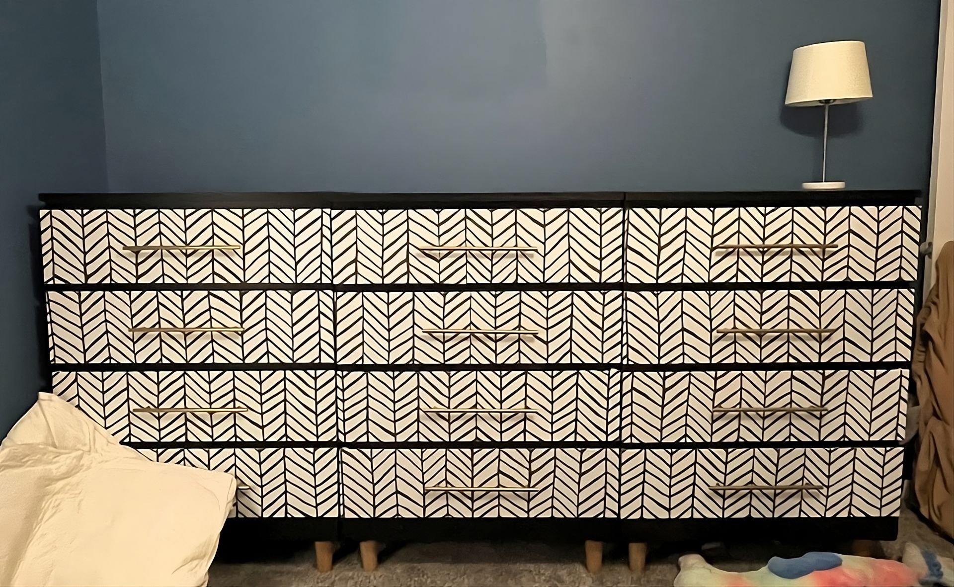 Kommode mit traditioneller Tapete im Chevron-Muster verziert, für einen modernen und eleganten Einrichtungsstil.