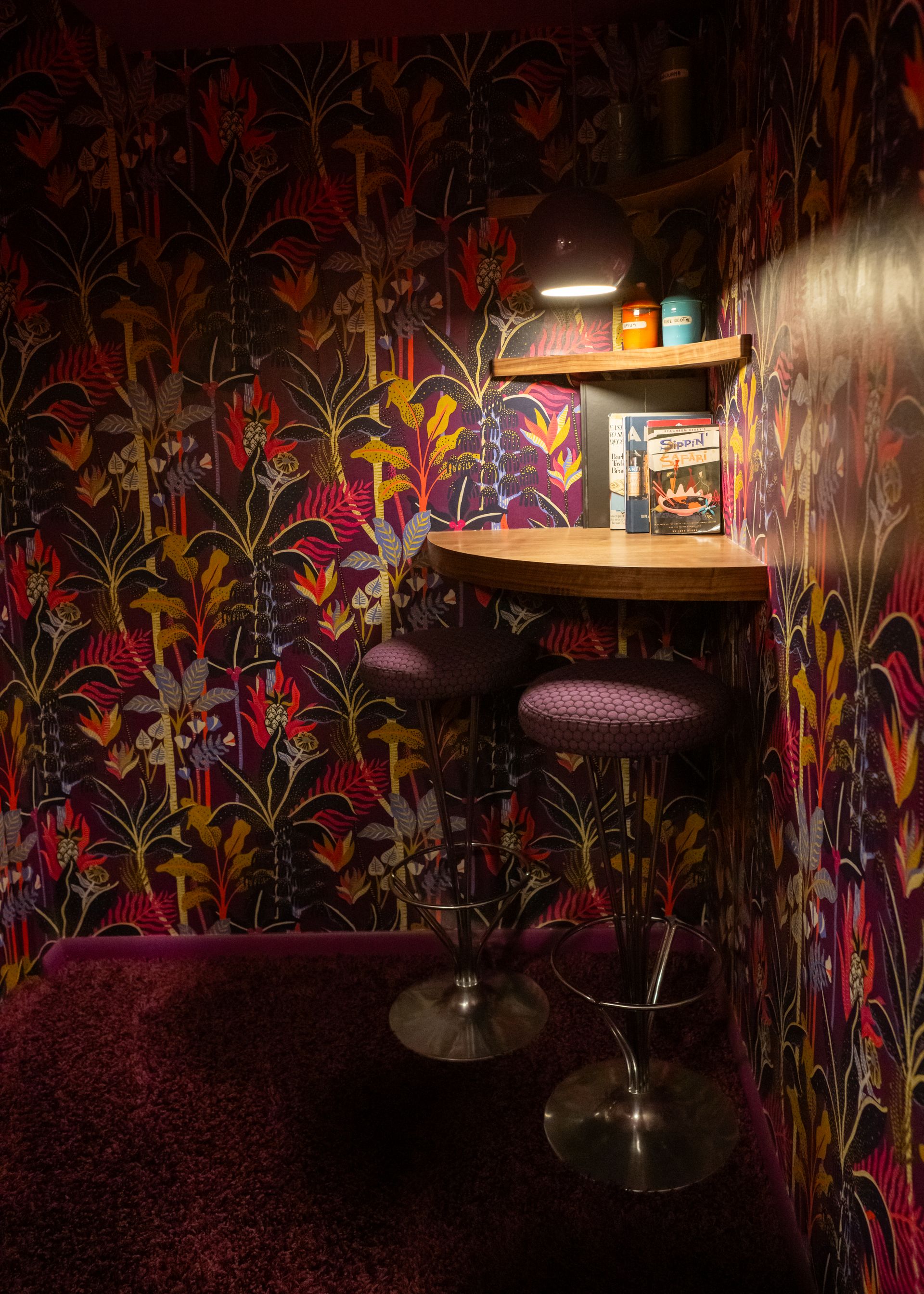 Chroma House Bar mit Speakeasy-Atmosphäre, hervorgehoben durch die violette Tropical-Dream-Tapete und passendes Vintage-Dekor.
